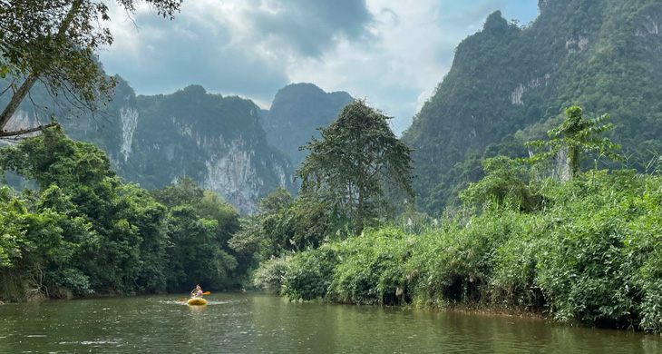 kayak on a river in jungle surrounded by mountains