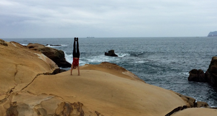 Handstand in front of the water shores in Yehliu Geopark